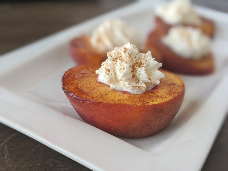 broiled cinnamon peaches and cream on a white plate