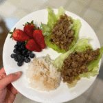 asian lettuce wraps on a plate with rice and berries