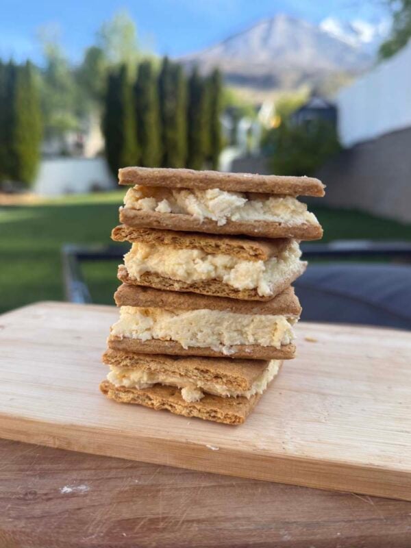 four protein graham cracker treats stacked on top of each other on a wood cutting board