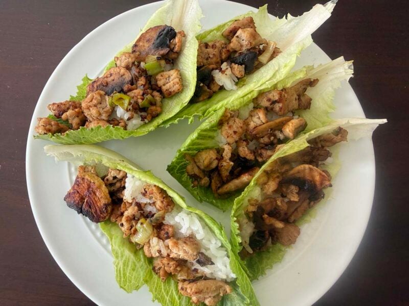 four chicken lettuce wraps on a white plate