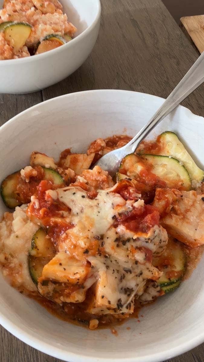 two chicken parmesan protein bowls, white bowls with a chicken parmesan zucchini mixture