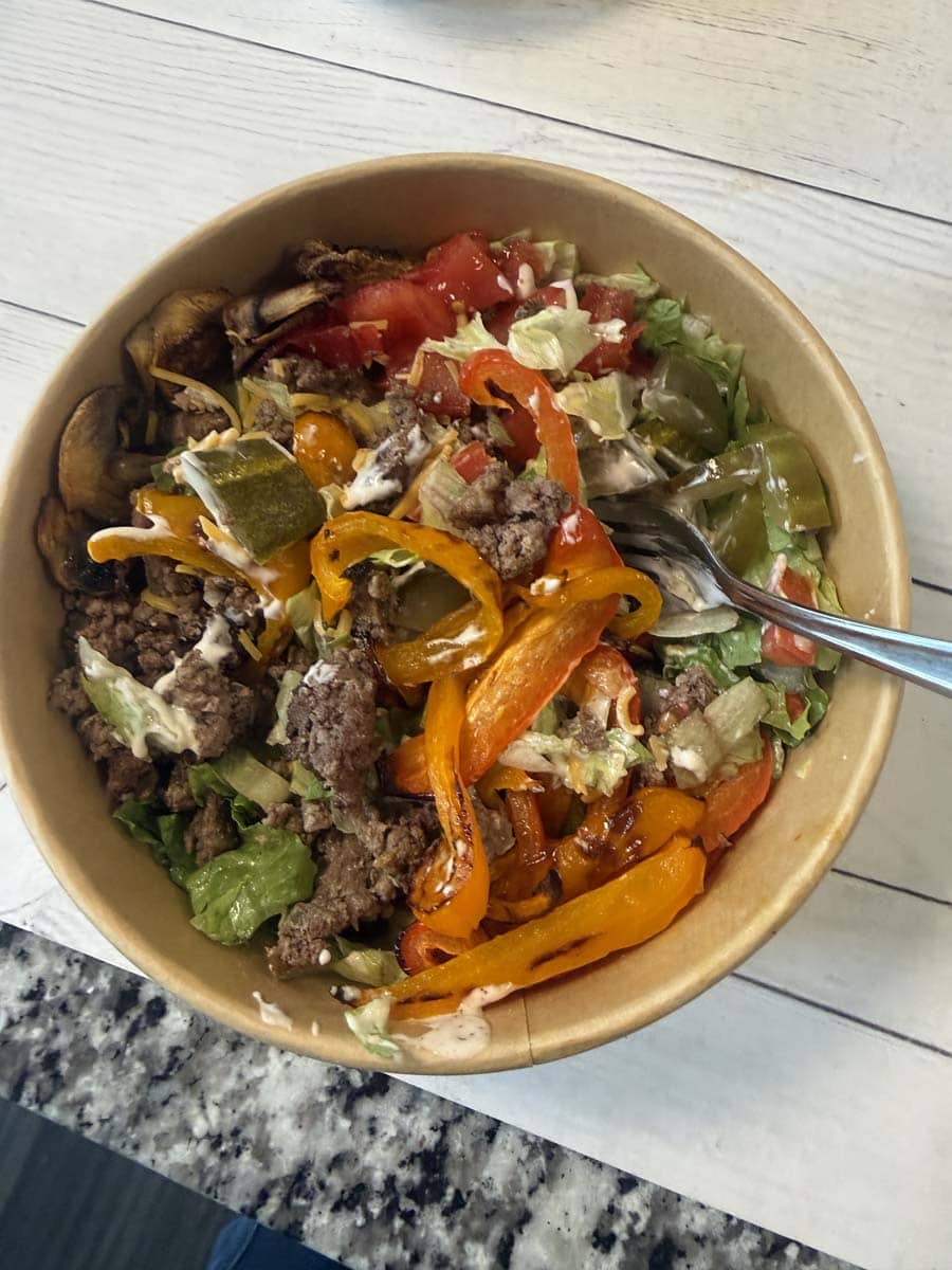 close up of a cheeseburger bowl in a brown bowl with a fork in it